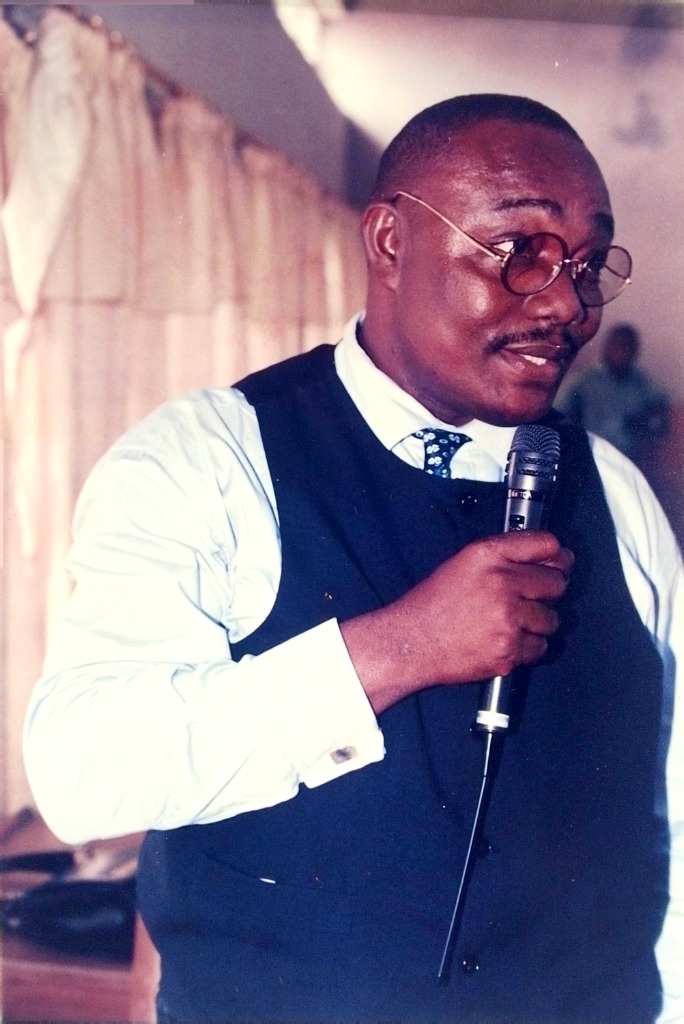 Apostle Prosper holding microphone during exhortation